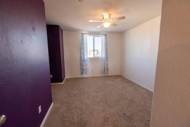 carpeted spare room featuring ceiling fan