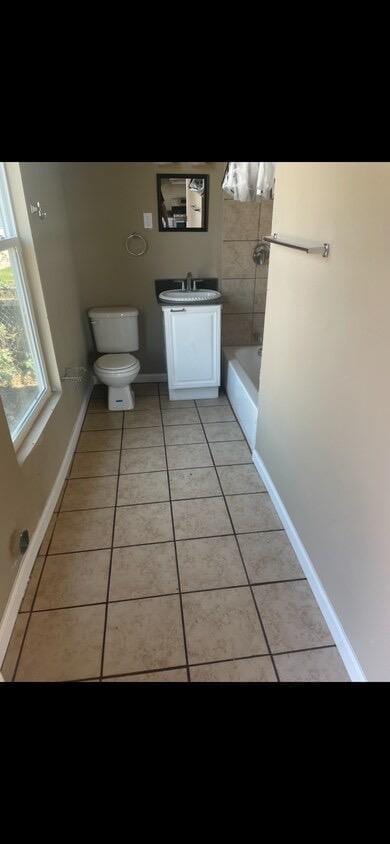 bathroom with toilet, a tub, tile patterned floors, and vanity