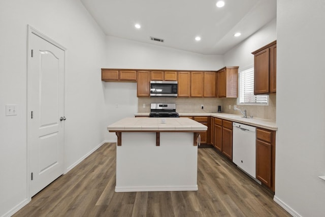 kitchen featuring stainless steel appliances, a center island, dark wood-type flooring, sink, and lofted ceiling