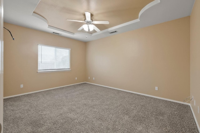 empty room featuring carpet flooring, ceiling fan, and a tray ceiling