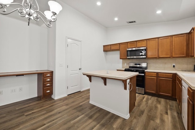 kitchen with vaulted ceiling, appliances with stainless steel finishes, hanging light fixtures, dark wood-type flooring, and backsplash