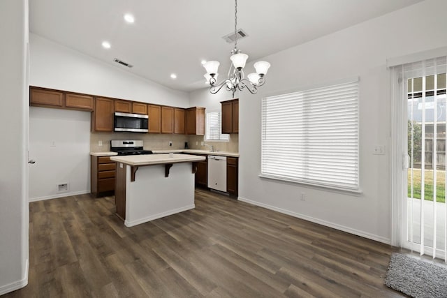 kitchen with stainless steel appliances, decorative light fixtures, an inviting chandelier, lofted ceiling, and a kitchen island