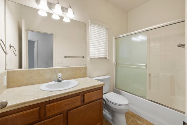 full bathroom with tile patterned flooring, shower / bath combination with glass door, vanity, and toilet