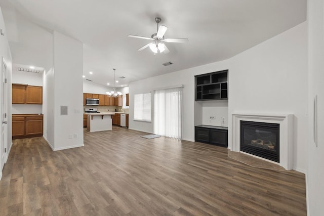 unfurnished living room with ceiling fan with notable chandelier, dark hardwood / wood-style flooring, and vaulted ceiling