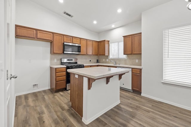 kitchen with vaulted ceiling, a center island, stainless steel appliances, decorative backsplash, and dark hardwood / wood-style flooring