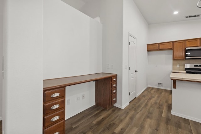 kitchen with vaulted ceiling, dark wood-type flooring, backsplash, and appliances with stainless steel finishes