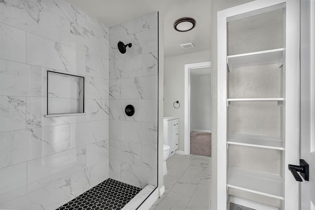 bathroom with a tile shower and toilet