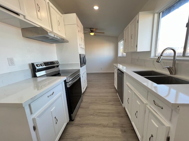 kitchen with appliances with stainless steel finishes, light hardwood / wood-style floors, ceiling fan, sink, and white cabinetry