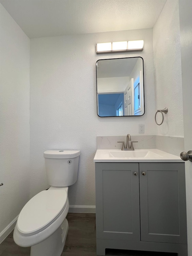 bathroom with toilet, vanity, and hardwood / wood-style flooring