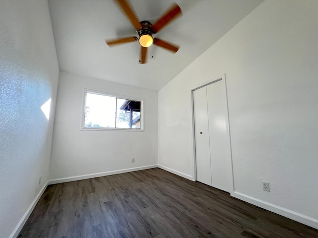 unfurnished bedroom with a closet, ceiling fan, vaulted ceiling, and dark wood-type flooring