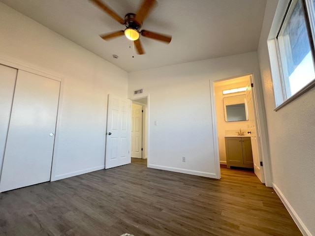 unfurnished bedroom with ceiling fan, connected bathroom, a closet, and dark hardwood / wood-style floors