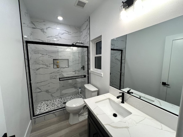 bathroom with a shower with door, wood-type flooring, toilet, and vanity