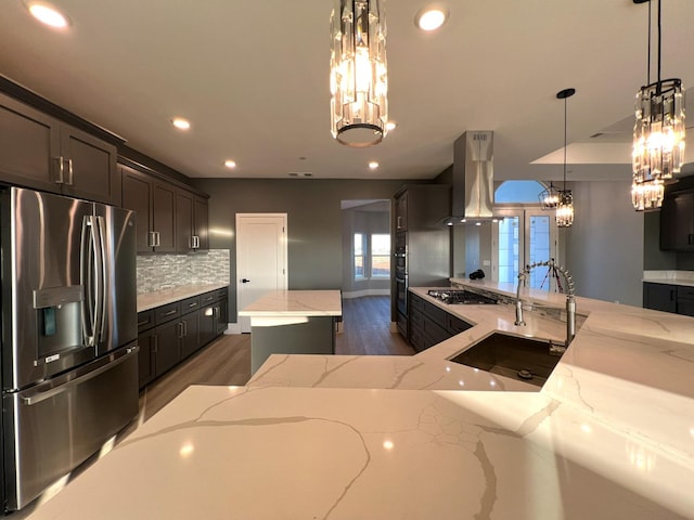 kitchen featuring light stone countertops, a kitchen island, stainless steel appliances, hanging light fixtures, and island range hood