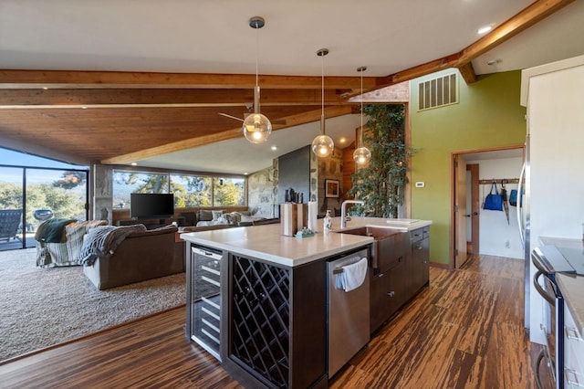 kitchen with hanging light fixtures, stainless steel appliances, an island with sink, beverage cooler, and dark hardwood / wood-style flooring