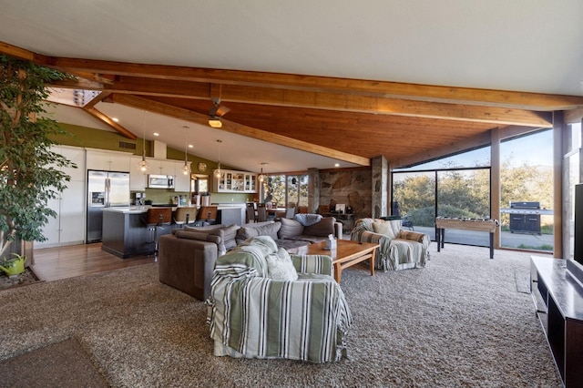 carpeted living room with ceiling fan and vaulted ceiling with beams