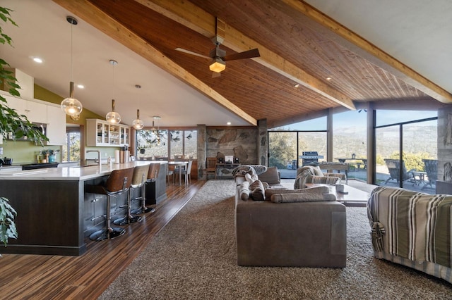 living room with lofted ceiling with beams, ceiling fan, a healthy amount of sunlight, and dark hardwood / wood-style floors