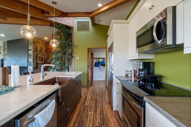 kitchen featuring white cabinets, lofted ceiling with beams, hanging light fixtures, and appliances with stainless steel finishes