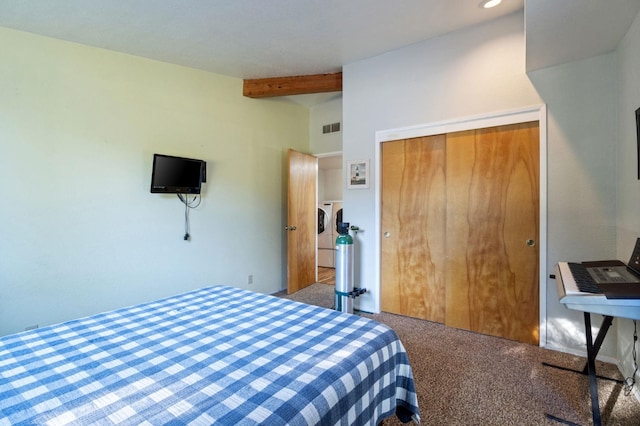 carpeted bedroom featuring a closet, separate washer and dryer, and beam ceiling