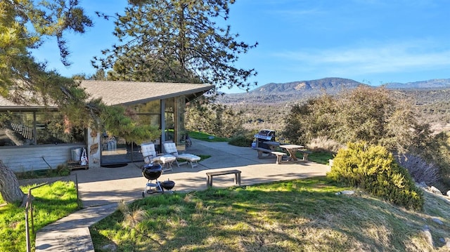 view of property's community featuring a patio, a yard, and a mountain view