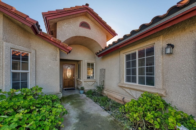 doorway to property with a tiled roof and stucco siding