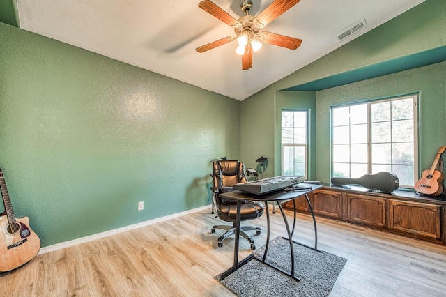 office featuring lofted ceiling, ceiling fan, visible vents, baseboards, and light wood finished floors