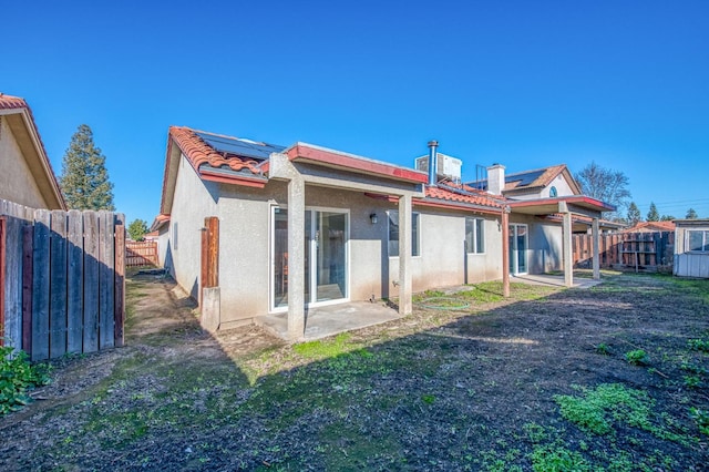 rear view of property featuring a fenced backyard, a yard, a tiled roof, and stucco siding