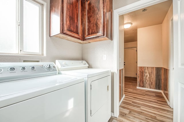 laundry room with cabinets, washing machine and dryer, and light wood-type flooring