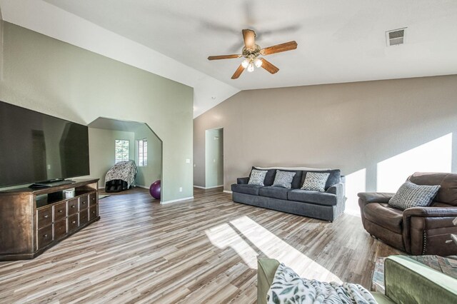 living room with ceiling fan, light hardwood / wood-style floors, and vaulted ceiling