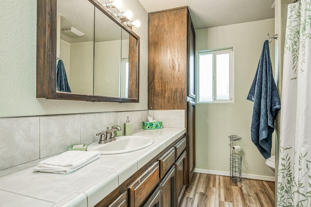 bathroom featuring hardwood / wood-style flooring, a textured ceiling, backsplash, and vanity