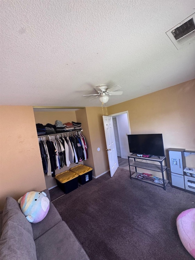 carpeted living room with a textured ceiling, visible vents, and a ceiling fan