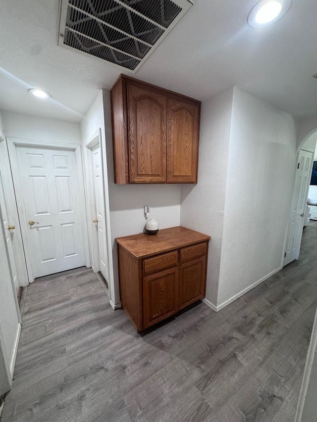 hall featuring arched walkways, wood finished floors, visible vents, and baseboards