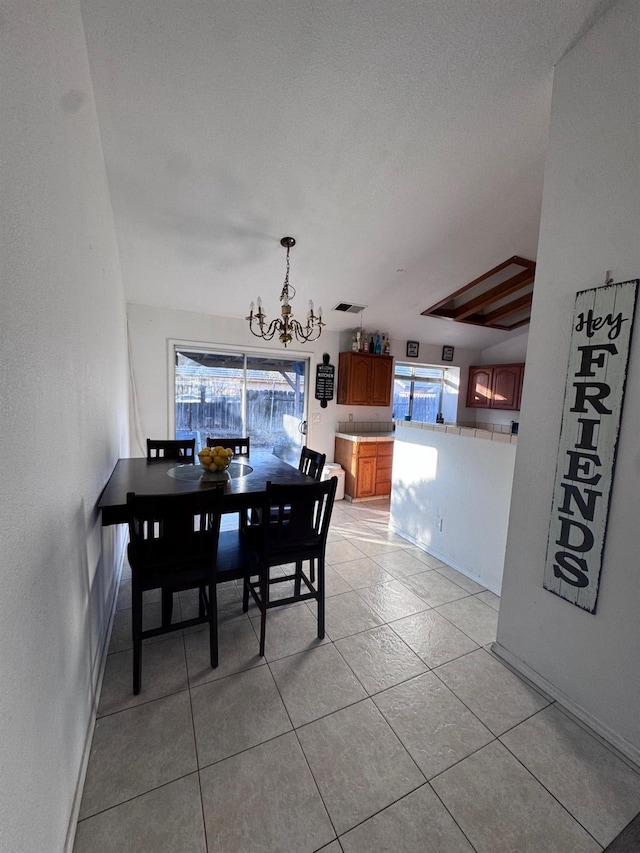 dining room featuring light tile patterned flooring, a healthy amount of sunlight, and a notable chandelier