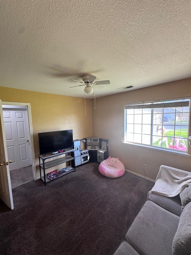 living room featuring carpet floors, visible vents, a textured ceiling, and a ceiling fan