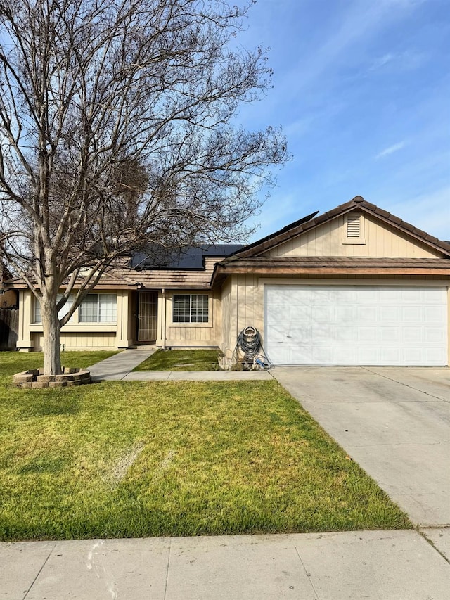 view of front of home featuring a garage, concrete driveway, solar panels, and a front yard