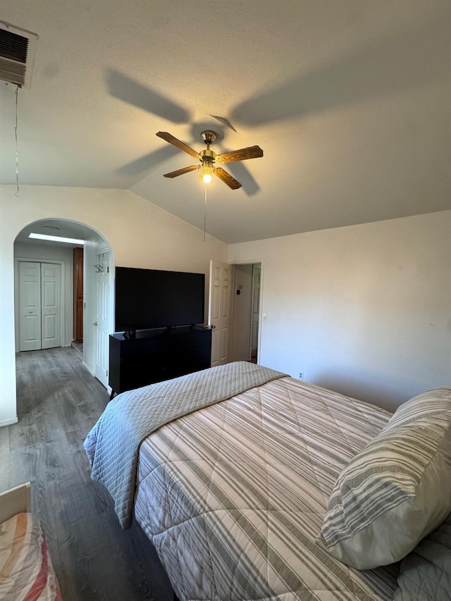 bedroom with arched walkways, visible vents, ceiling fan, vaulted ceiling, and wood finished floors