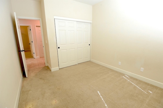 unfurnished bedroom featuring a closet and light colored carpet