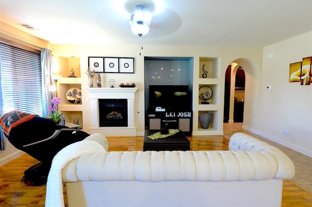 living room with ceiling fan, hardwood / wood-style flooring, and built in shelves