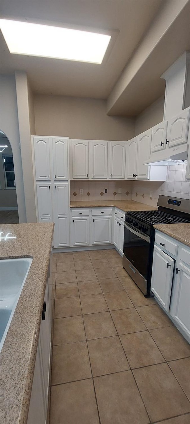 kitchen with decorative backsplash, stainless steel range with gas cooktop, and white cabinets