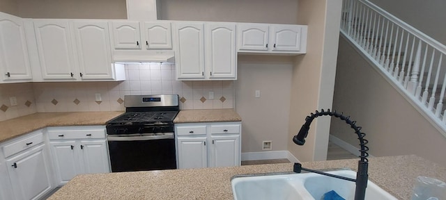 kitchen featuring stainless steel gas stove, white cabinets, tasteful backsplash, and sink