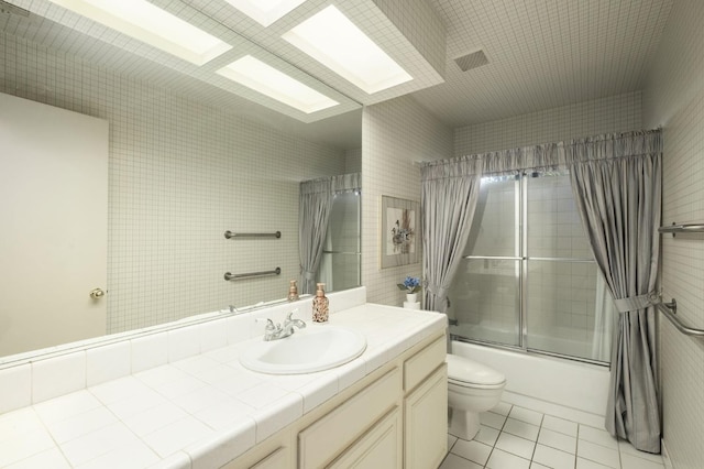 full bath with a skylight, toilet, shower / bath combination with glass door, tile patterned flooring, and vanity