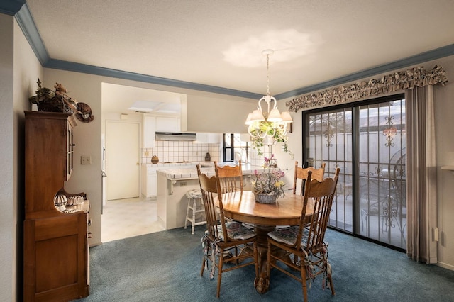 dining room with carpet floors, ornamental molding, and an inviting chandelier