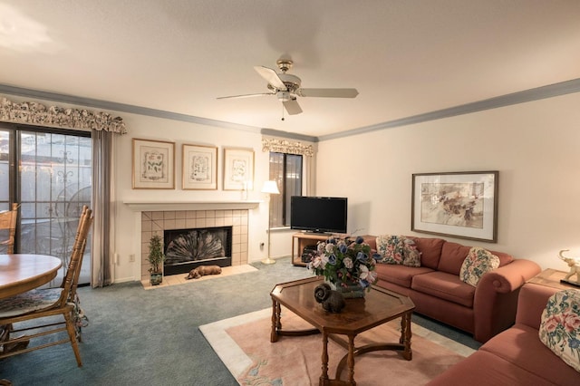 carpeted living area with a tiled fireplace, a ceiling fan, and crown molding