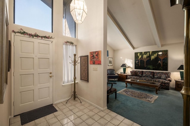 foyer featuring light tile patterned floors, baseboards, light colored carpet, beamed ceiling, and a high ceiling