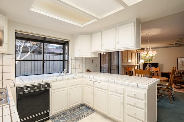 kitchen with a peninsula, black dishwasher, tile counters, and white cabinets