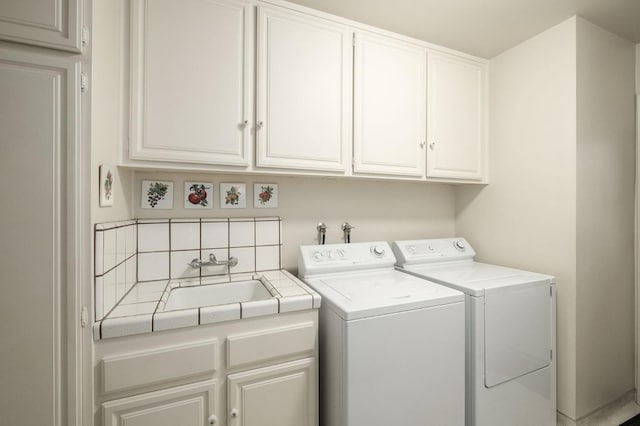 clothes washing area featuring cabinet space, a sink, and washing machine and clothes dryer