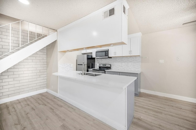 kitchen featuring kitchen peninsula, stainless steel appliances, a textured ceiling, and white cabinetry