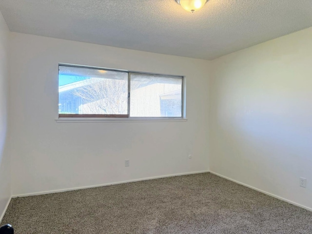 carpeted empty room featuring a textured ceiling