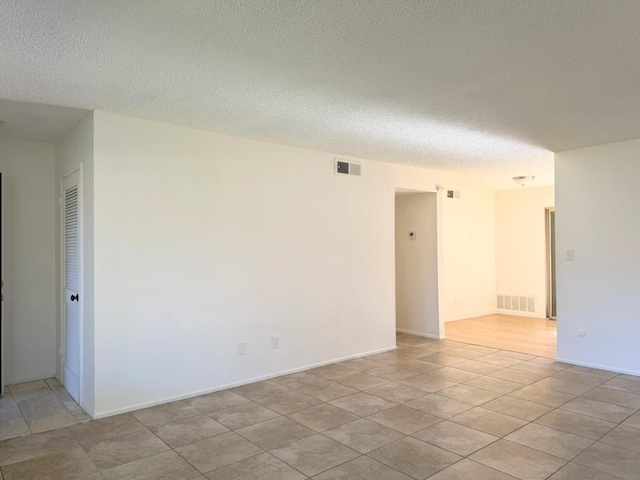 unfurnished room with a textured ceiling and light tile patterned floors