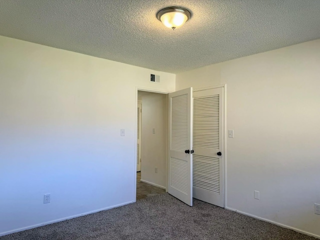 unfurnished bedroom with dark carpet, a closet, and a textured ceiling