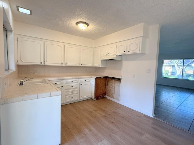 kitchen with white cabinets, light wood-type flooring, and sink